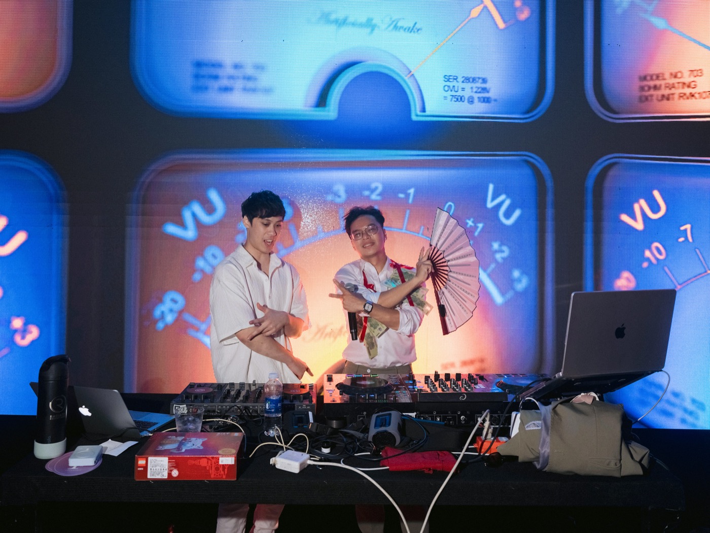 Two DJs performing in front of a VU-meter video wall